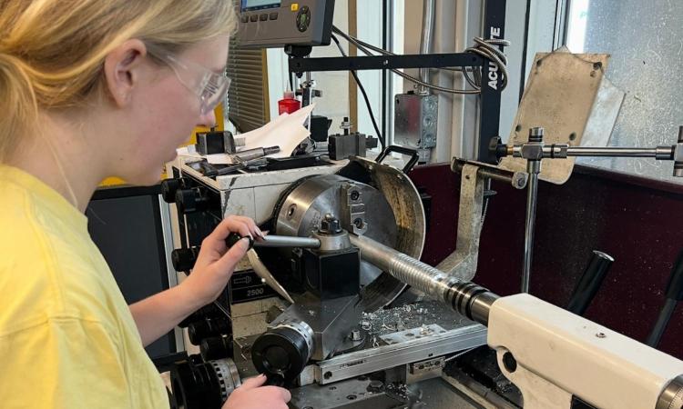 Lauren Thompson working on a metal working machine in the Flowers Invention Studio.